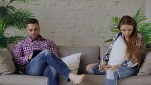 Two people sitting apart on a sofa, illustrating the pursue-withdraw cycle in a relationship